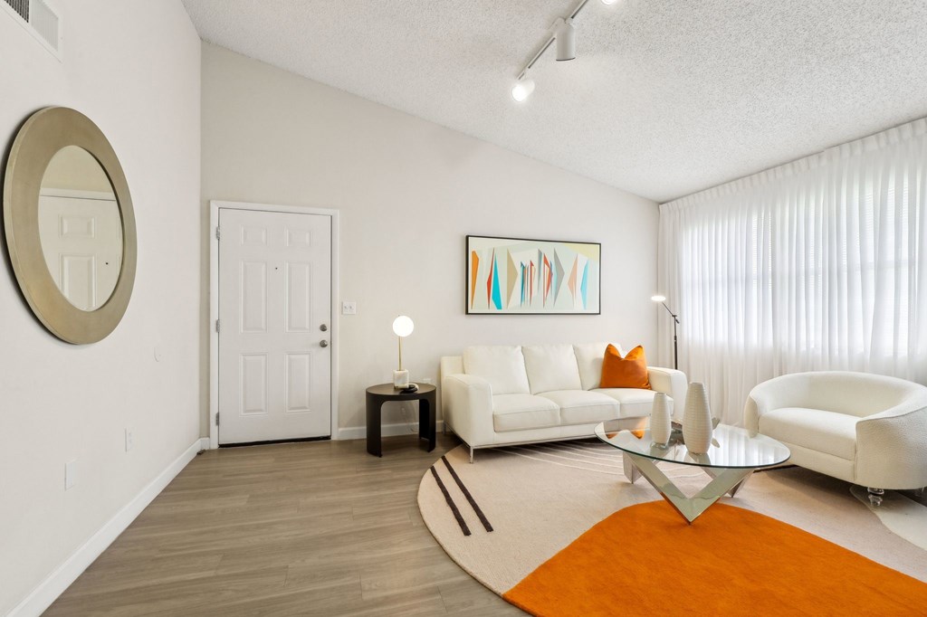A living room with a white couch, a coffee table, and a painting on the wall.
