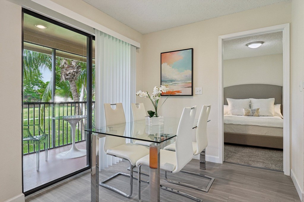 A dining room with a glass table and chairs and a painting on the wall.