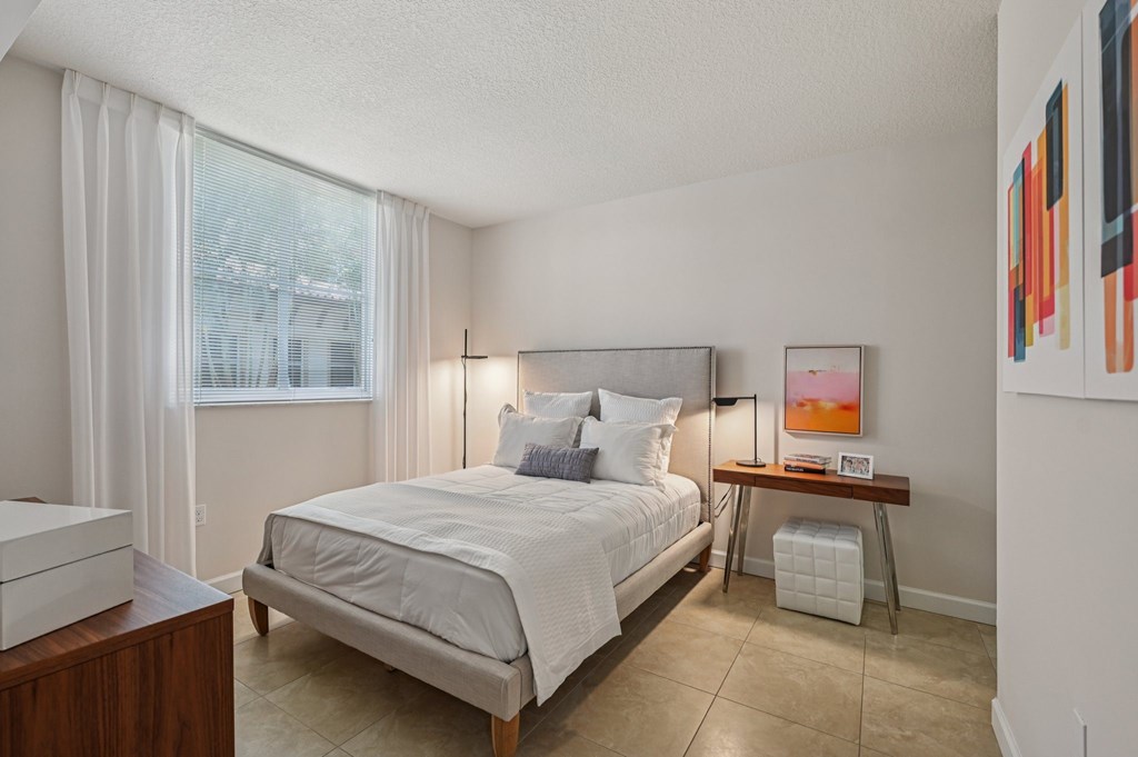 A bedroom with a large bed and a window with curtains.