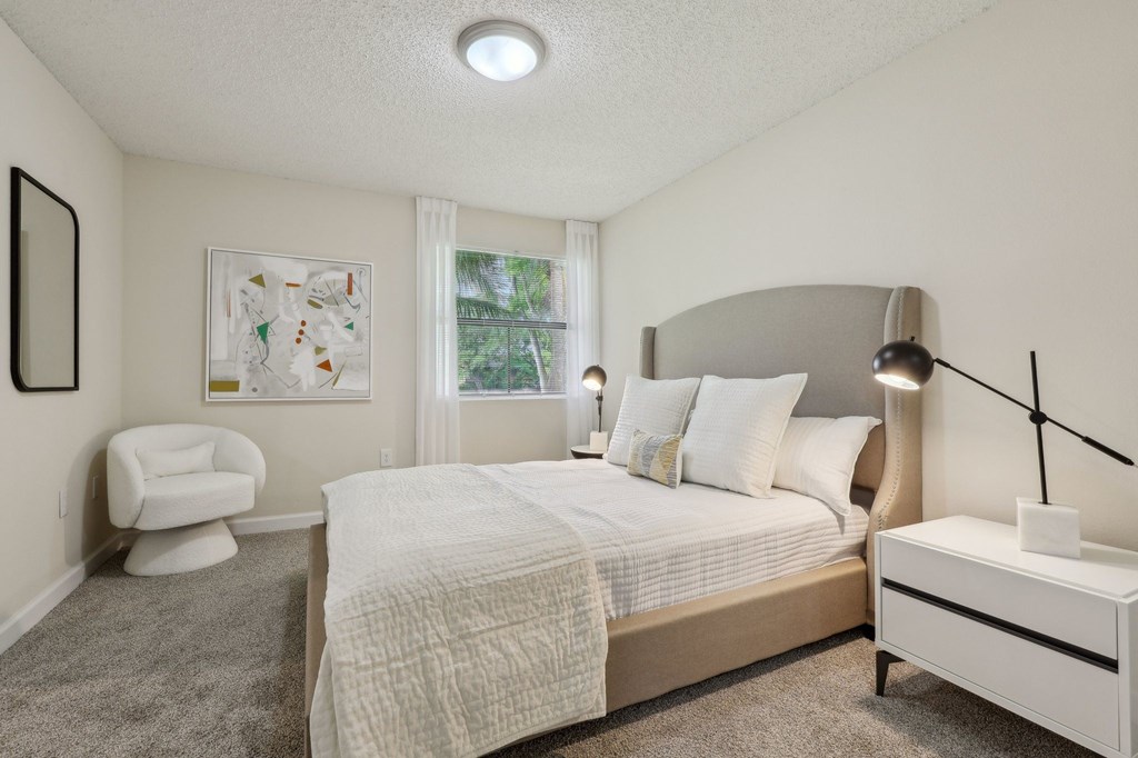 A bedroom with a bed, chair, and lamp.