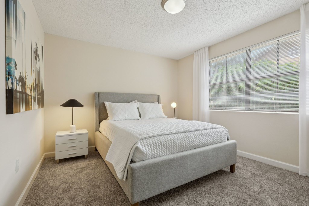 A bedroom with a large bed and a nightstand with a lamp.