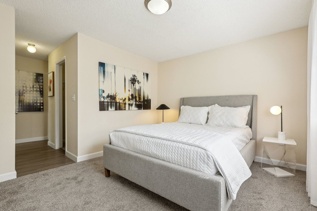 A bedroom with a large bed and a painting on the wall.