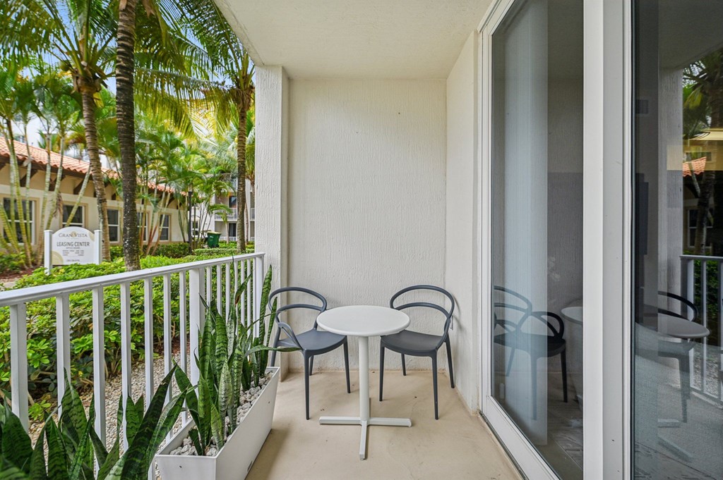 A balcony with a table and chairs overlooking a garden.