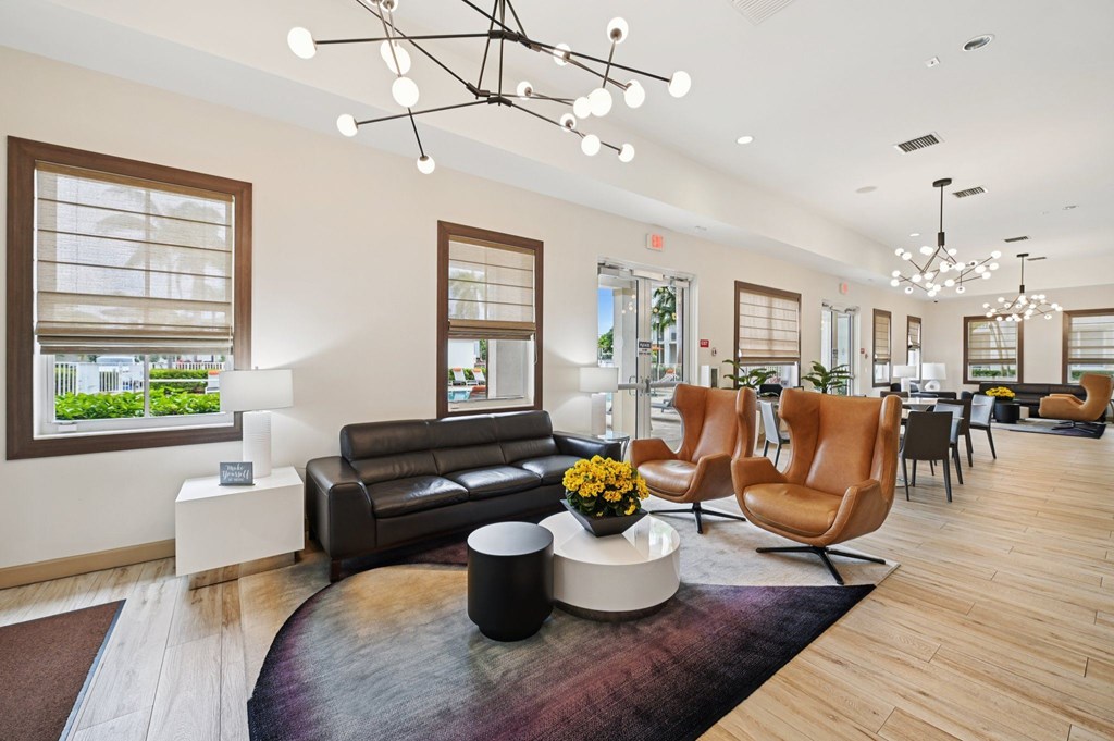 A modern living room with a brown leather couch and a coffee table with a vase of flowers on it.