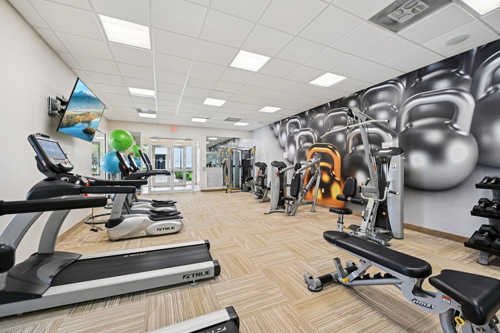 A gym with a variety of equipment including treadmills, weights, and exercise machines.