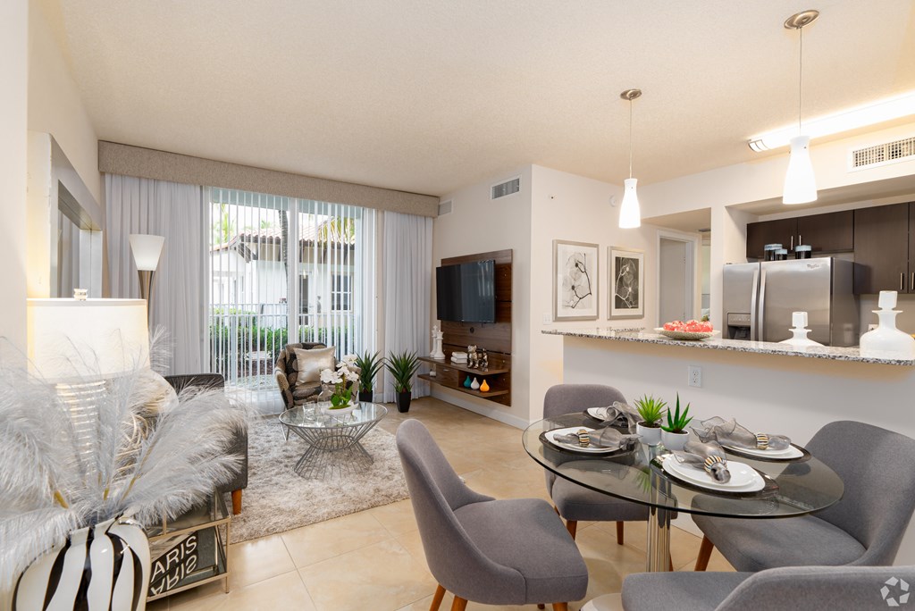 A modern living room with a glass table and grey chairs.