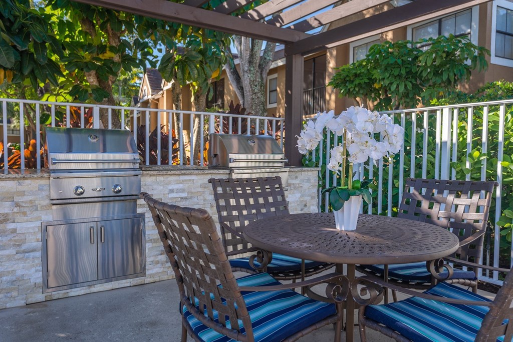 A patio with a table, chairs, and a grill.
