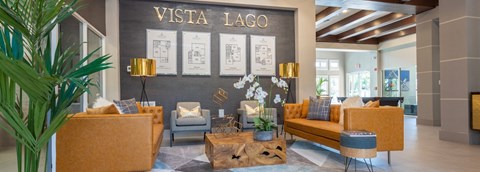 A living room with a couch, chairs, and a coffee table in front of a wall with the text "VISTA LAGO".