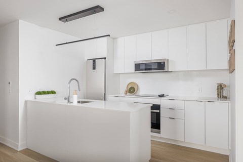 A modern kitchen with white cabinets and a white countertop.