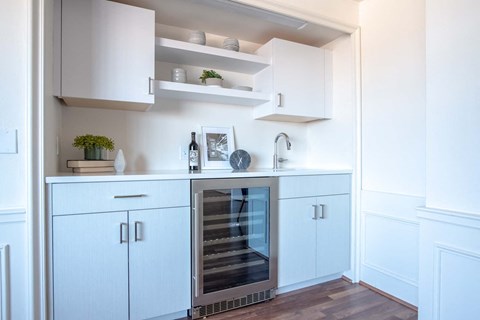 a white kitchen with blue cabinets and a wine refrigerator