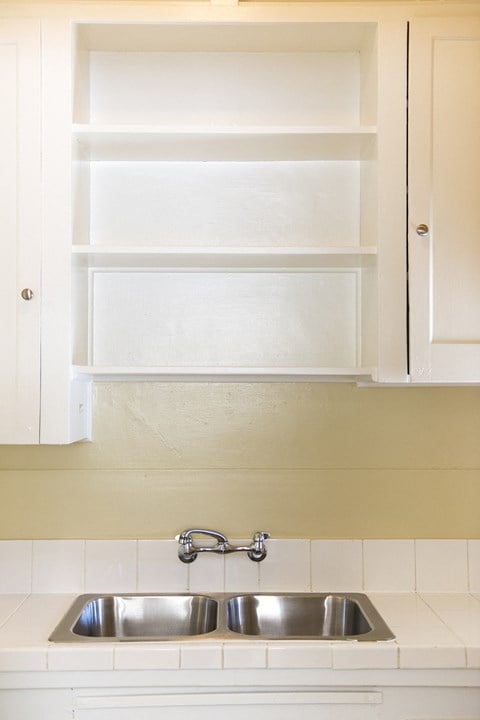 a kitchen with white cabinets and a sink and a cabinet above it