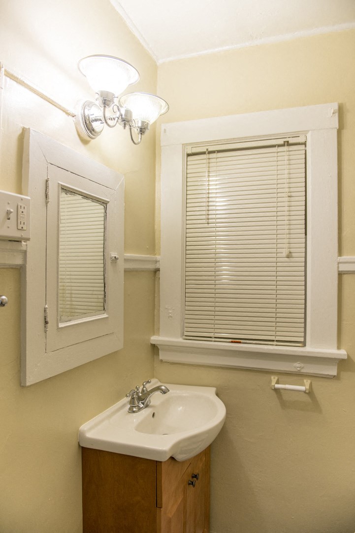 a bathroom with a sink and a window and a mirror