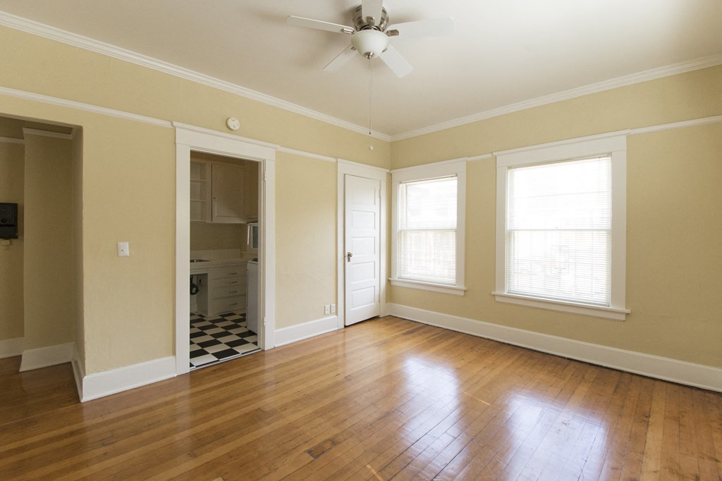 an empty living room with wood floors and a ceiling fan