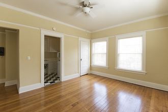 an empty living room with wood floors and a ceiling fan