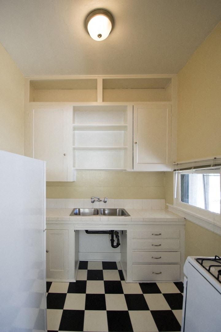 an empty kitchen with a checkered floor and a sink