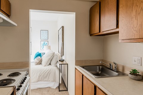 a kitchen with a sink and a bedroom in the background