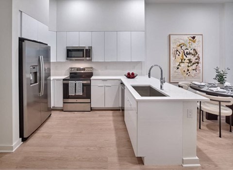 A modern kitchen with white cabinets and a stainless steel refrigerator.