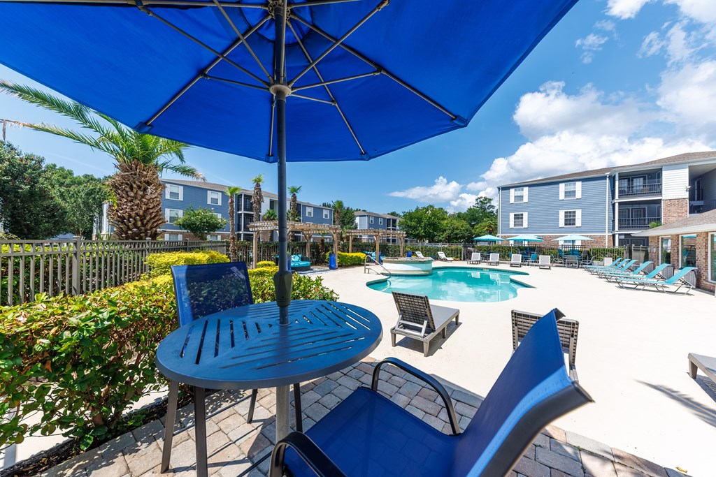 A blue umbrella is above a table with chairs around it.