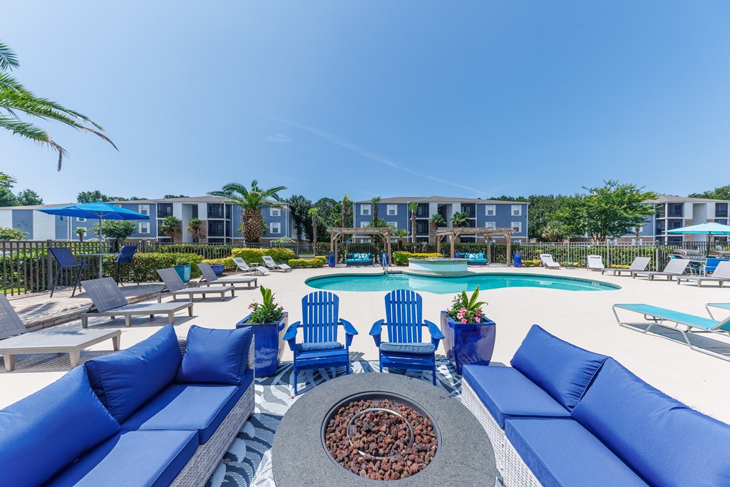 A pool area with blue couches and chairs.