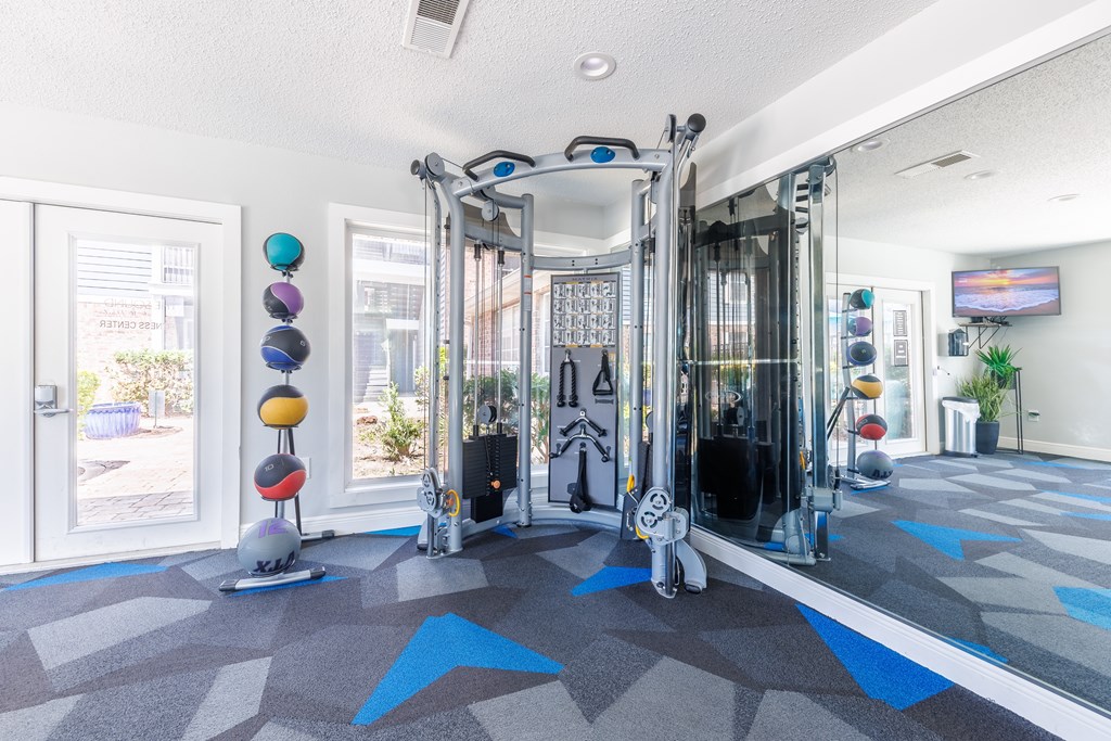 A gym with a variety of equipment including a treadmill, weights, and a stationary bike.
