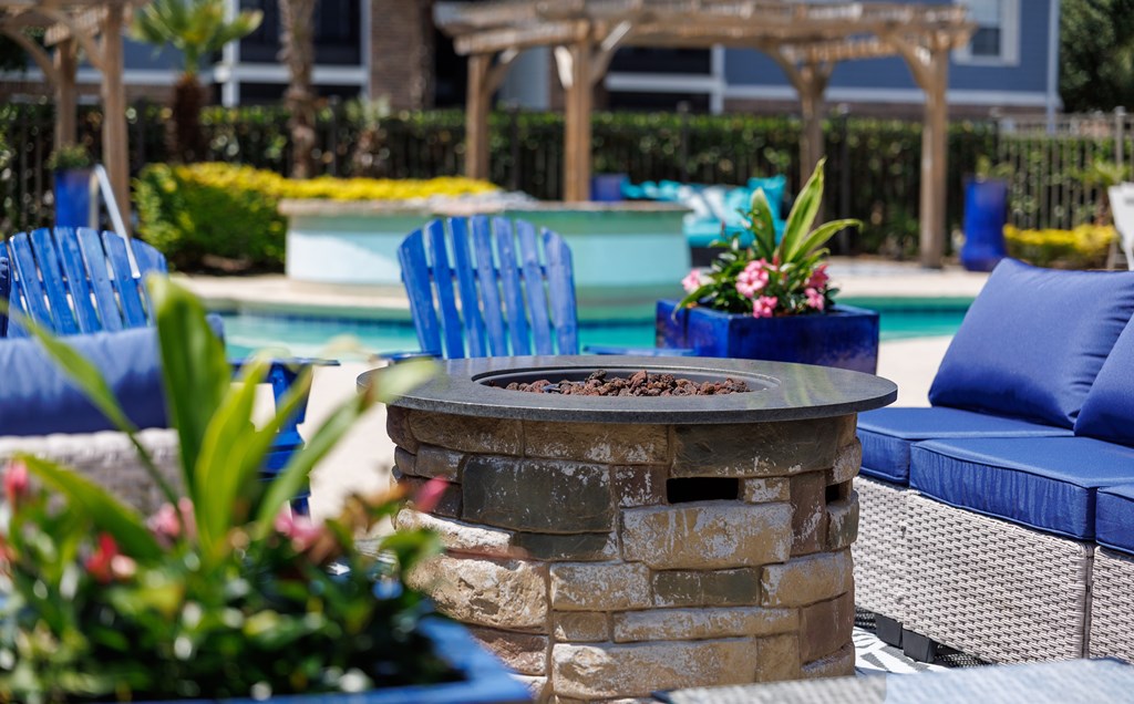 A patio with a fire pit and chairs.