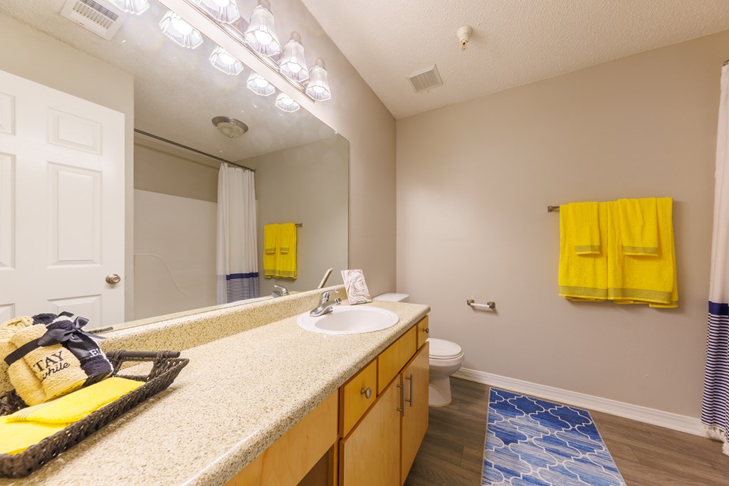 A bathroom with a sink, mirror, and yellow towels.