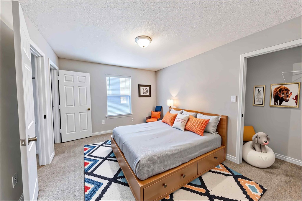 A bedroom with a bed, a rug, and a picture on the wall.