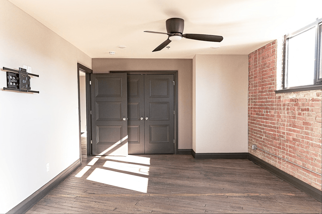 A room with a ceiling fan and a large door.