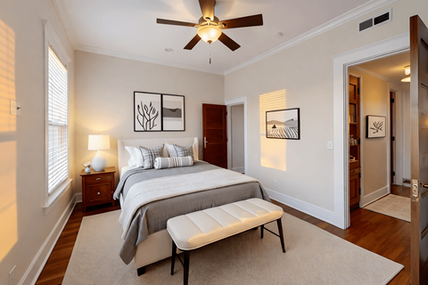 A bedroom with a bed, a bench, and pictures on the wall.