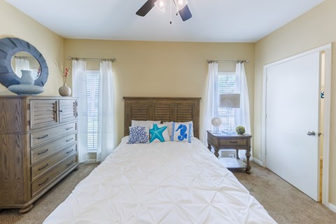A bedroom with a large bed, a dresser, and a ceiling fan.