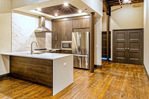A kitchen with a white island and wooden floors.