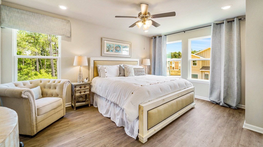 A bedroom with a large bed, a chair, and a ceiling fan.