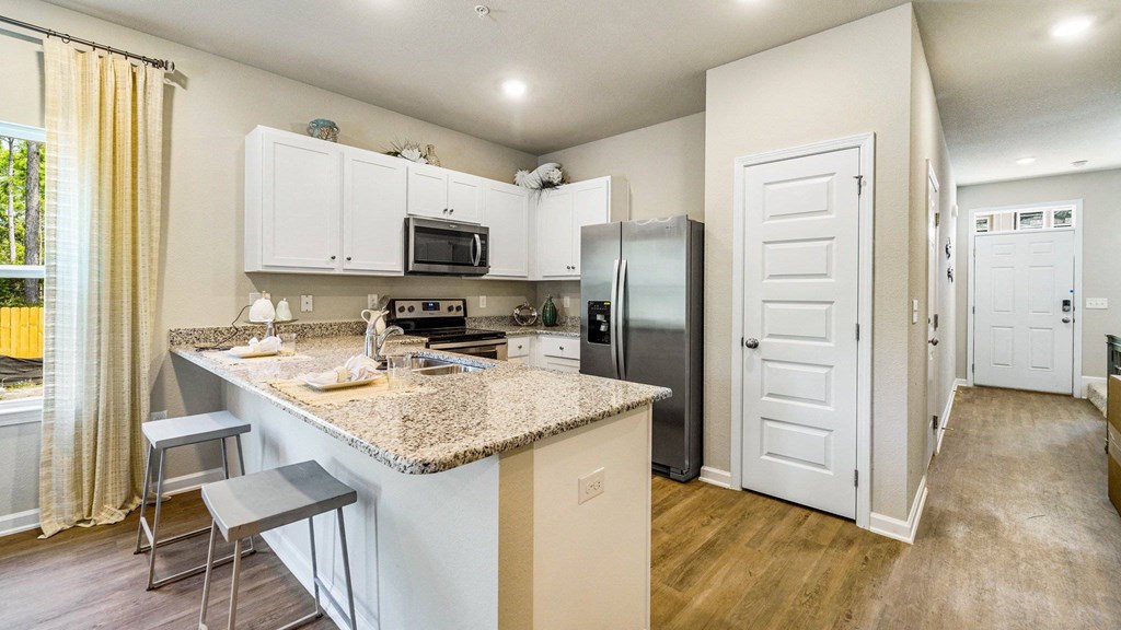 A kitchen with a granite countertop and stainless steel appliances.