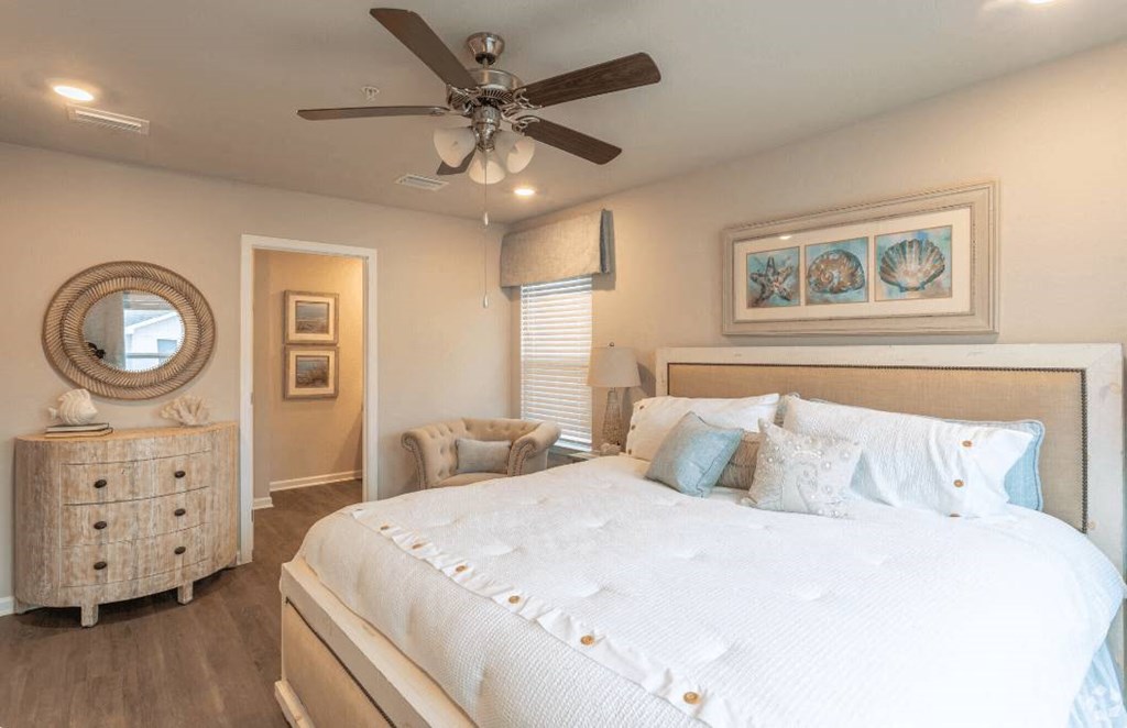 A bedroom with a large bed, a dresser, and a ceiling fan.