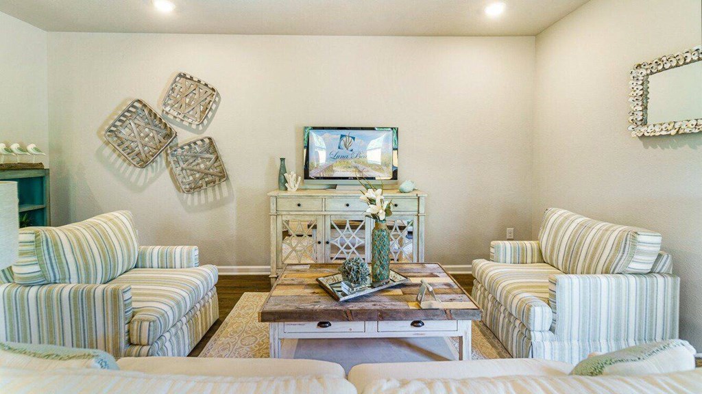 A living room with a striped couch and a coffee table with a vase on it.