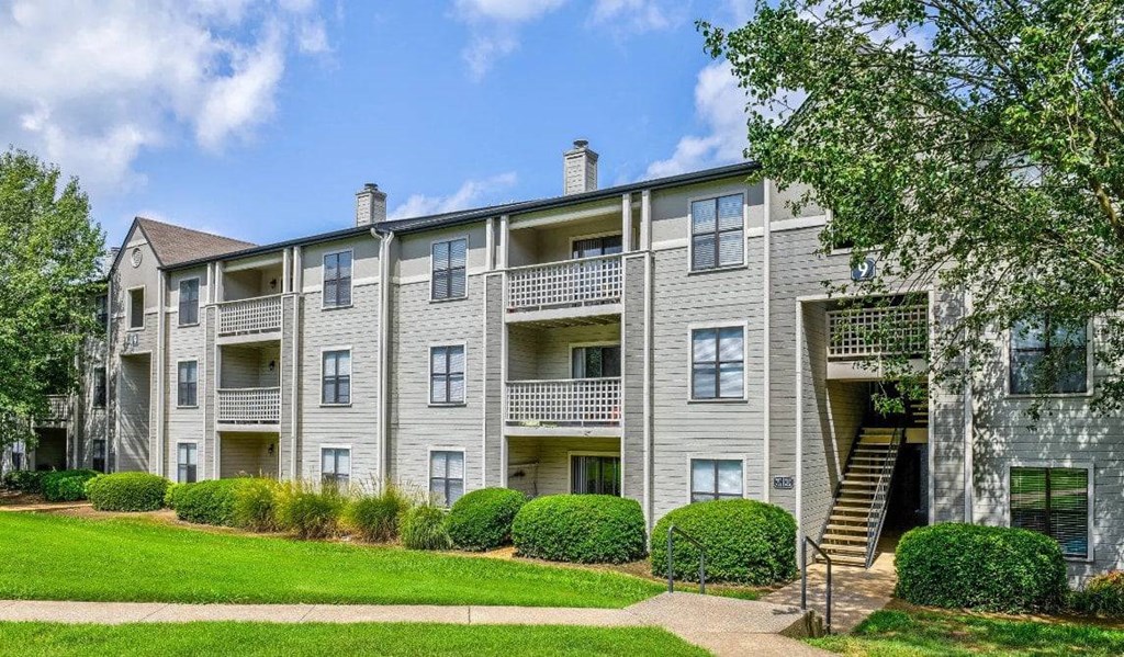 A large apartment building with a green lawn in front.