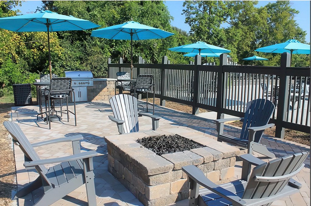 A patio with a fire pit and chairs.