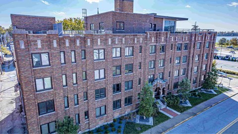 A large red brick building with a flat roof and a chimney on the top floor.