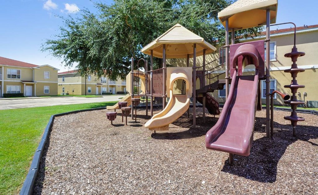 A playground with a red slide and a yellow canopy.