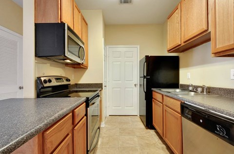 A kitchen with a black refrigerator and black microwave.