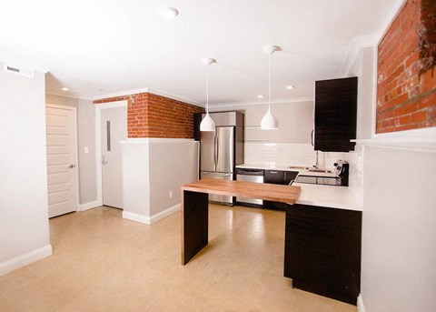 A kitchen with a brick wall and a wooden island.