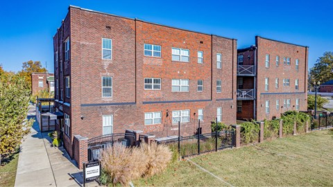 A red brick building with a black fence in front.