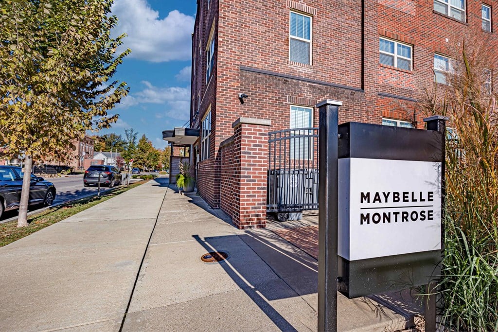 A sign that says Maybelle Montrose in front of a brick building.