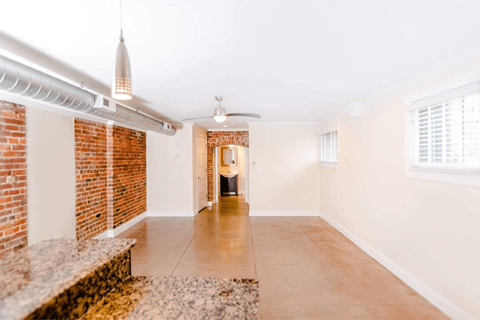 A room with a brick wall and a ceiling fan.