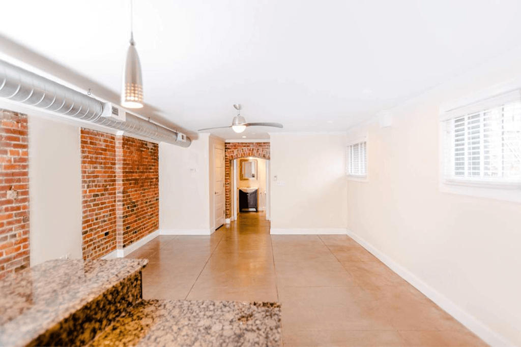 A room with a brick wall and a ceiling fan.