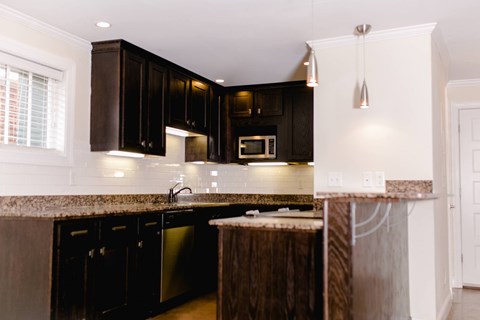 A kitchen with black cabinets and a granite countertop.