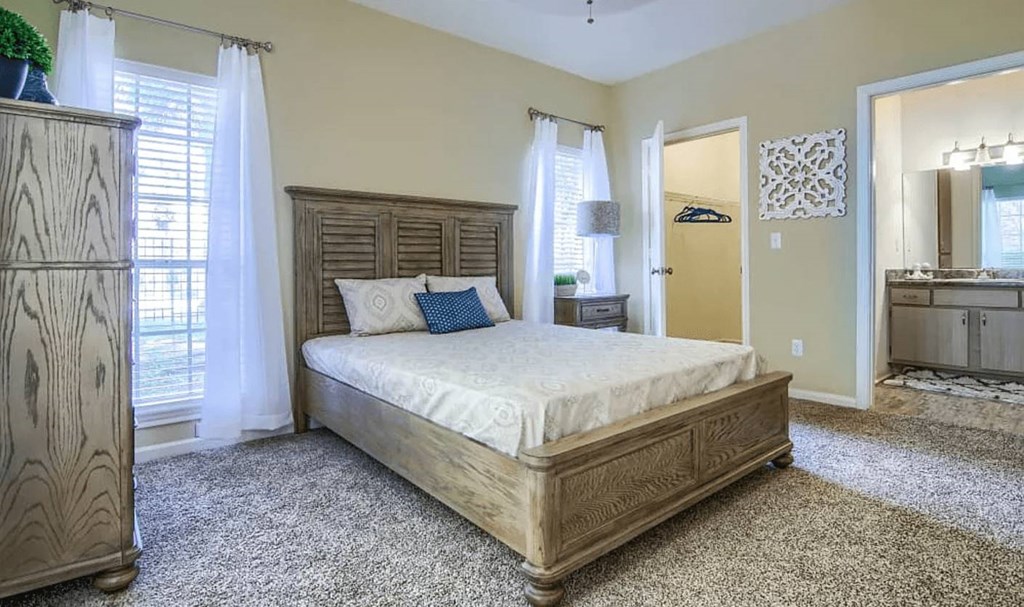A bedroom with a large bed and a wooden dresser.
