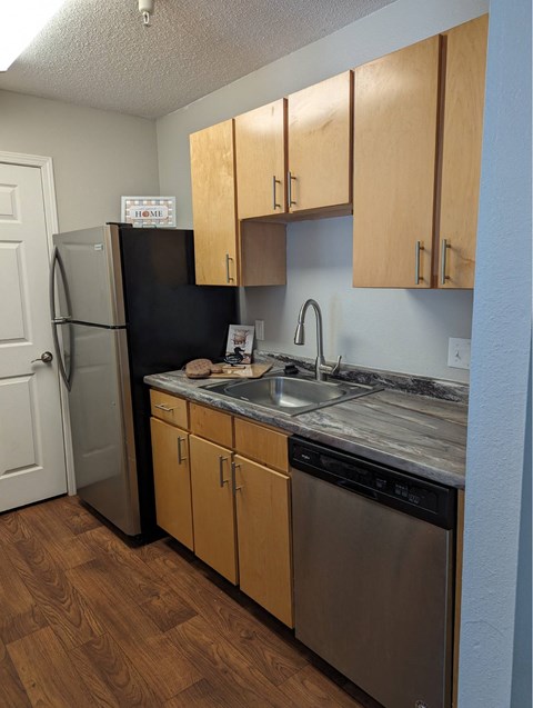 A kitchen with wooden cabinets and a black fridge.