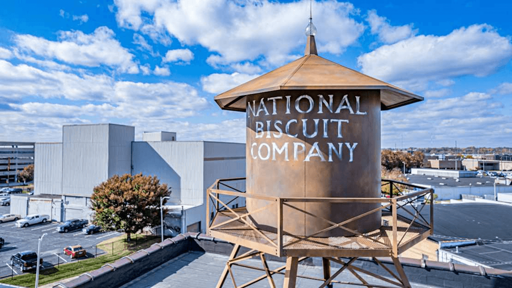 A large sign for the National Biscuit Company stands in front of a building.