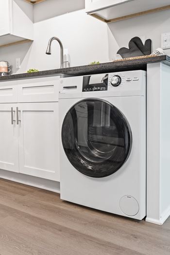 A white front loading washing machine in a kitchen at The Preserve at Pine Valley Apartments, Wilmington, North Carolina